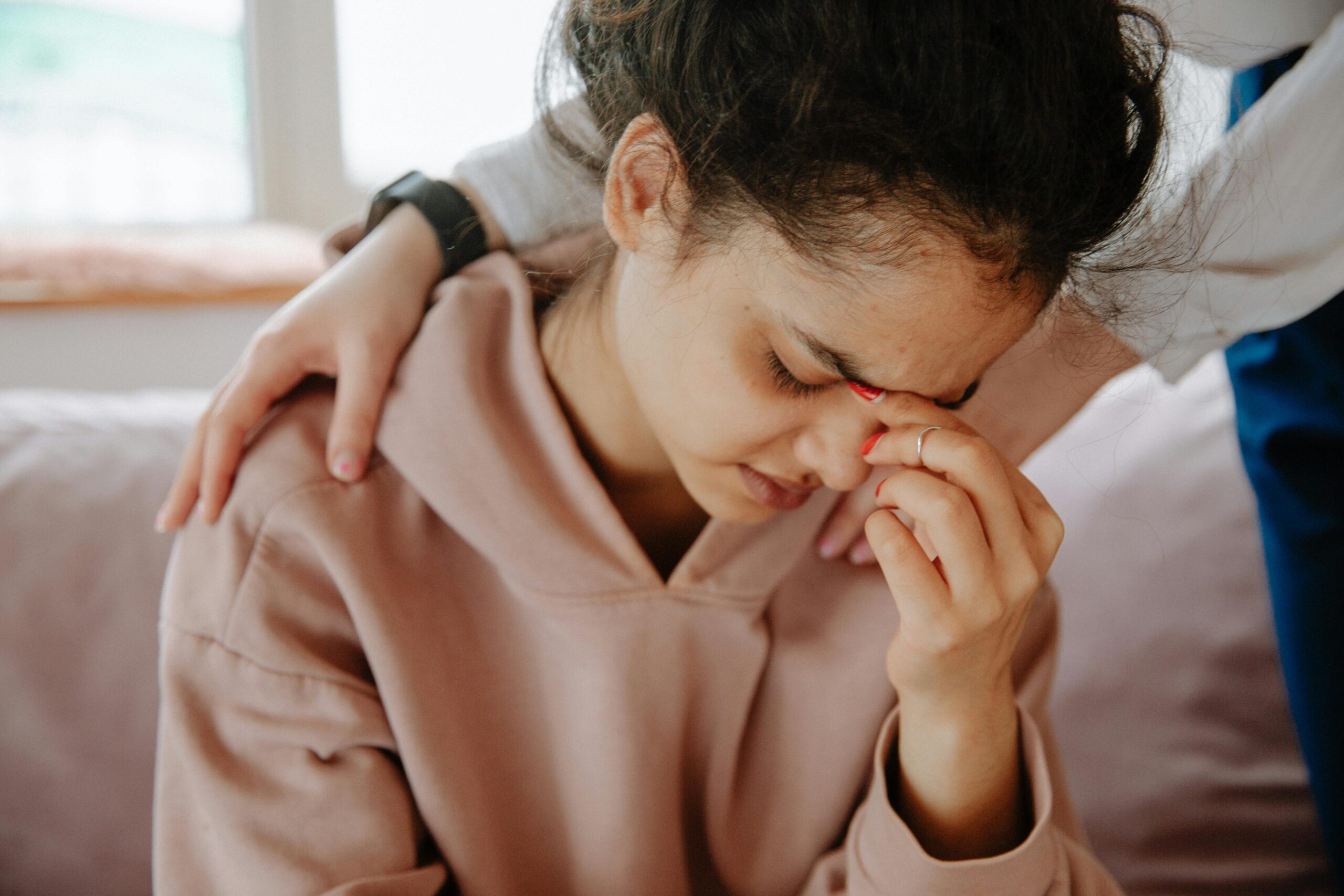 A distressed woman receives comfort from someone beside her while considering abortion and the importance of a trusted support system.
